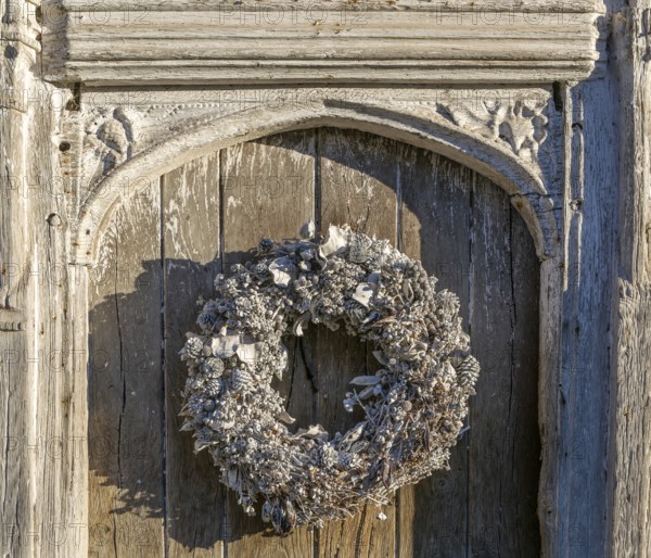 Silver white Christmas wreath on ancient old door in Lavenham, Suffolk, England, UK