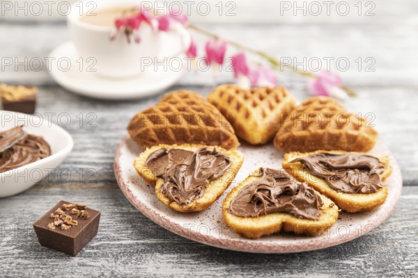 Homemade waffle with chocolate butter and cup of coffee on a gray wooden background. side view, selective focus, close up