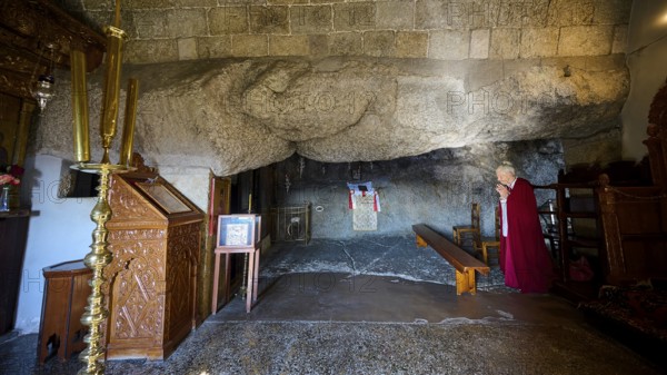 Praying woman in a sacred space with rock walls and an altar, rock grotto, Monastery tis Apokalipsis, Patmos, Dodecanese, Greek Islands, Greece, Europe