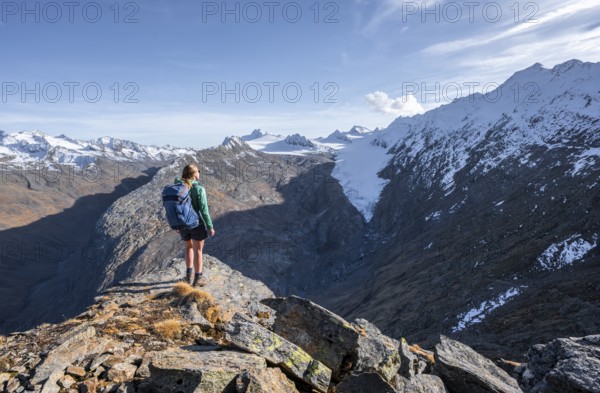 Mountaineer standing on a rock, surrounded by an impressive mountain landscape with snow-covered peaks in autumn View of Gurgler Ferner with summit Hochwilde and Falschungsspitze, Ötztal Alps, Tyrol, Austria, Europe