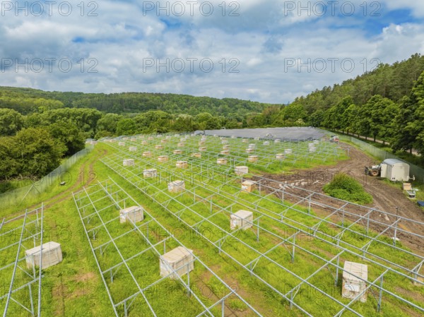 Solar panels on a green area under a cloudy sky in the middle of a wooded landscape, construction of the Black Forest Nature solar park, Weil der Stadt, Germany, Europe