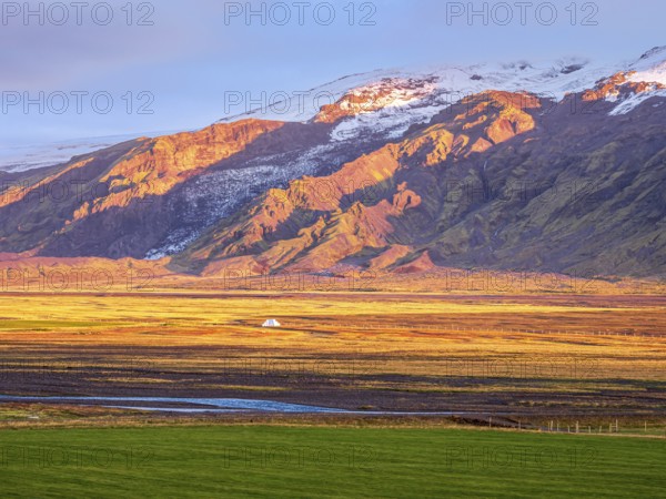 View over meadows to glacier Eyjafjallajökull, Fljotsdalur valley, warm light at sunset, Iceland, Europe