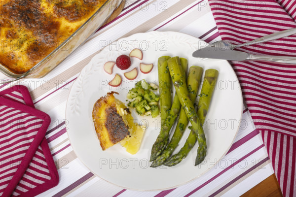 South German cuisine, green asparagus with rhubarb vinaigrette and potato gratin, healthy, vegetables, served on a plate, vegetarian, cutlery, knife, fork, casserole dish with gratin, gratinated, traditional cuisine reinterpreted, food photography, studio, Germany, Europe