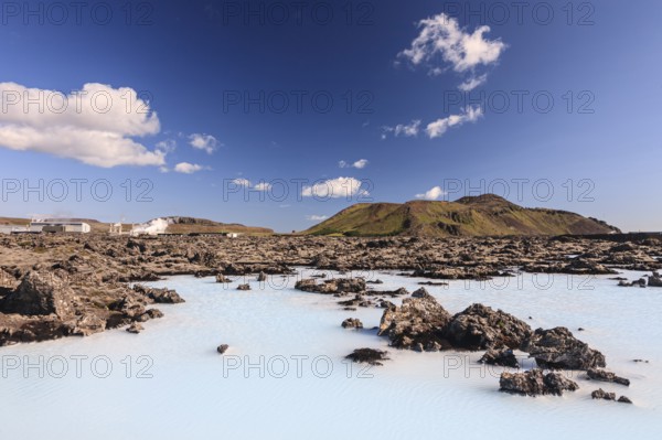 Outdoor thermal pool and geothermal power plant in front of volcanic mountains, Blue Lagoon, summer, sunny, Grindavik, Reykjanes, Iceland, Europe