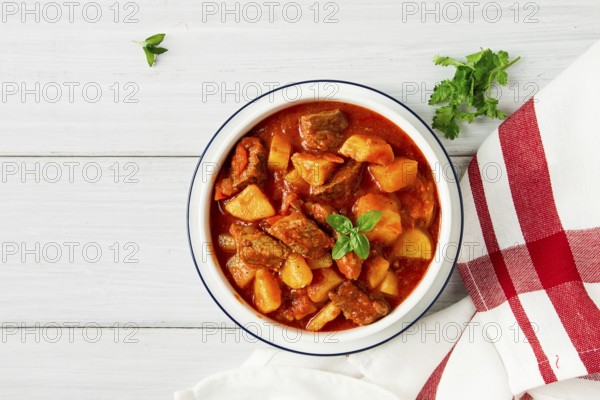 Potatoes stewed with meat, in tomato sauce, with spices and herbs, no people, on a white table