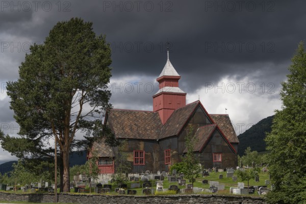 Old church and tree-covered cemetery under a dramatic sky, Dovre church, Dovre kyrkje, Dovre, Fylke Innlandet, upper Gudbrandsdalen, Norway, Europe