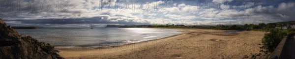Extensive sandy beach overlooking the sea, cloudy skies and tranquil natural scenery, Ballycastle