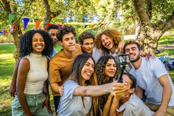Smiling multi-ethnic friends taking selfie with wearable camera at park while celebrating birthday