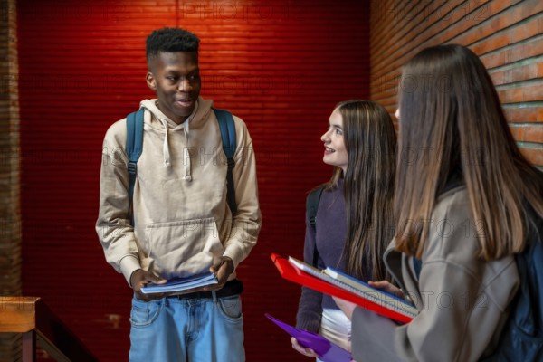 Group of cheerful multi ethnic students talking and smiling together on school hallway during break time