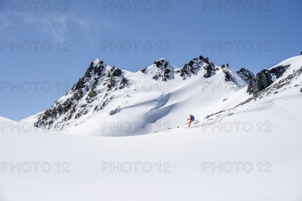 Ski tourer on the descent, minimalist winter landscape, white snow and dark mountains on the Scalettahorn, Graubünden, Switzerland, Europe