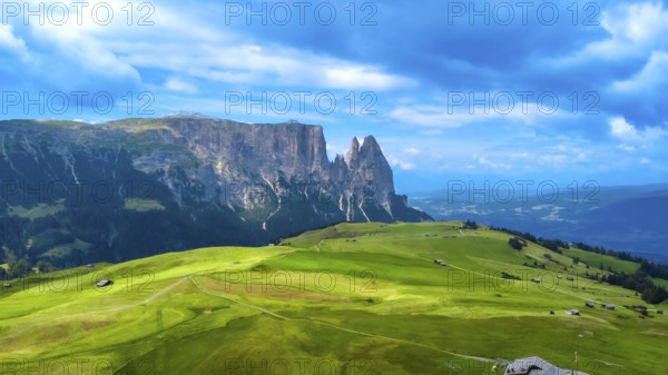 Breathtaking summer landscape featuring lush green meadows, rolling hills, and the majestic peaks of the sassolungo group in the italian dolomites