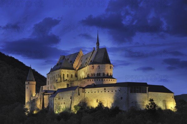 The fortified Vianden Castle illuminated at night in Luxembourg