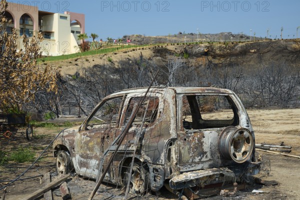 A burnt-out car stands in a destroyed landscape, destroyed trees and a building in the background, forest fires, summer 2023, forest fire damage, Boutique 5 Hotel, Kiotari, Rhodes, Rhodes, Dodecanese, Greek Islands, Greece, Europe