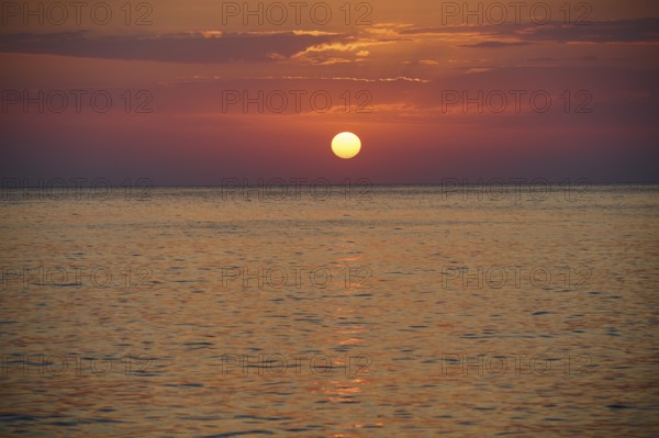 Sunset over the calm sea under an orange sky, Mandraki, Nisyros, Dodecanese, Greek Islands, Greece, Europe