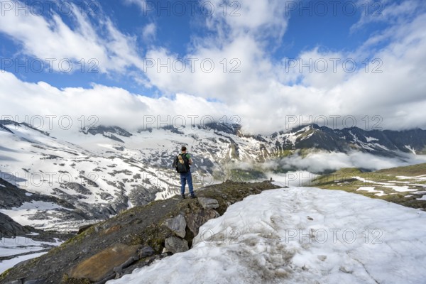 Mountaineer on hiking trail between snowfields, mountain landscape with summit Hoher Weißzint and Hochsteller with glacier Schlegeiskees, Berliner Höhenweg, Zillertal Alps, Tyrol, Austria, Europe