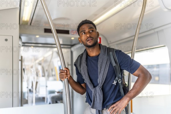 African young man travelling by public transportation standing on an intercity train