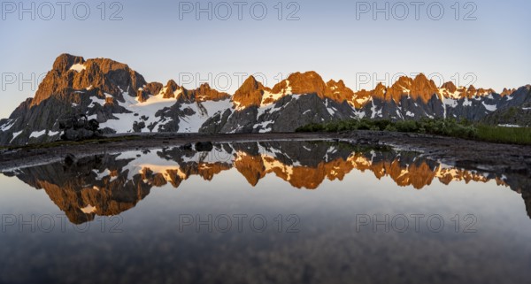 Rocky mountain peaks reflected in a small pond, mountain landscape with alpenglow at sunrise, at the Trollfjord Hytta, at the Trollfjord, Lofoten and Vesterålen, Nordland, Norway, Europe