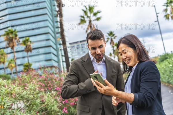 Multi-ethnic business coworkers using phone and smiling standing in a tropical modern city