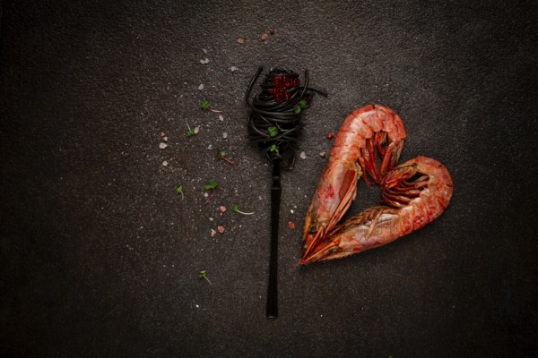 Black spaghetti, wrapped on a fork, langoustines in the shape of a heart, on the table, dish concept, dish background, top view