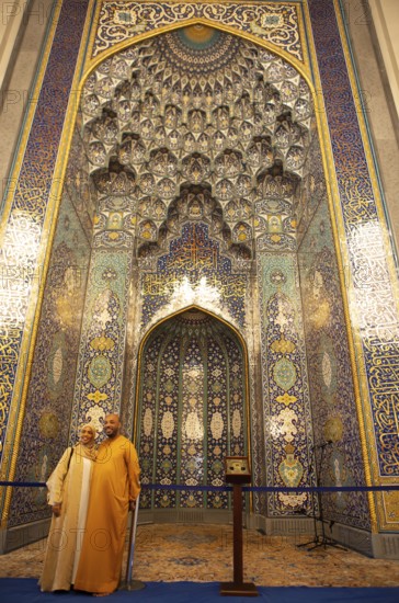Omani couple in traditional dress in front of the golden prayer niche in the Sultan Qabus Grand Mosque, Muscat, Muscat Province, Oman, Asia