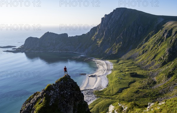 Climber on a rock, view of picturesque coastal landscape, steep coast with peak Måtind or Måtinden, Høyvika beach and sea, hike to the summit of Måtind, Andøya island, Vesterålen, Nordland, Norway, Europe
