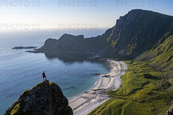 Climber on a rock, view of picturesque coastal landscape, steep coast with peak Måtind or Måtinden, Høyvika beach and sea, hike to the summit of Måtind, Andøya island, Vesterålen, Nordland, Norway, Europe