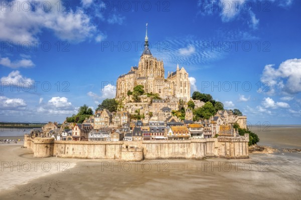 Majestic abbey on a mountain in a vast landscape under a partly cloudy sky, Le Mont-Saint-Michel