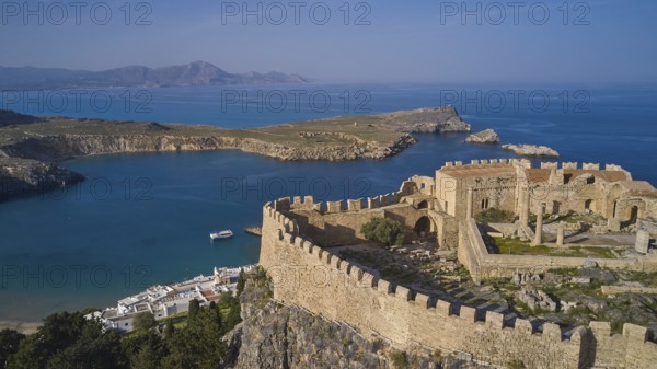 Drone shot, Acropolis of Lindos, Late afternoon light, Ancient fortress on a headland above a blue bay with a boat in the water, Archaeological site, Lindos, Rhodes, Dodecanese, Greek Islands, Greece, Europe