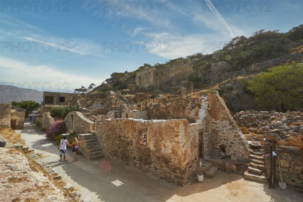 Tourists walking through an ancient village with ruins and pathways on a sunny day, Venetian Sea Fortress, Leper Island, Spinalonga, Elounda Bay, Mirabello Bay, East Crete, Crete, Greek Islands, Greece, Europe