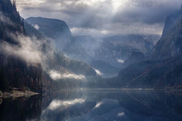 The Vordere Gosausee in autumn. The Dachstein in clouds. Rays of sunshine shine through the clouds. Forest shrouded in clouds. Vorderer Gosausee, Gosau, Gosau Valley, Salzkammergut, Upper Austria, Austria, Europe