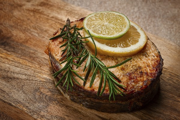 Salmon steak, fried, on a cutting board, top view, rosemary, lemon and lime, homemade, one serving, no people