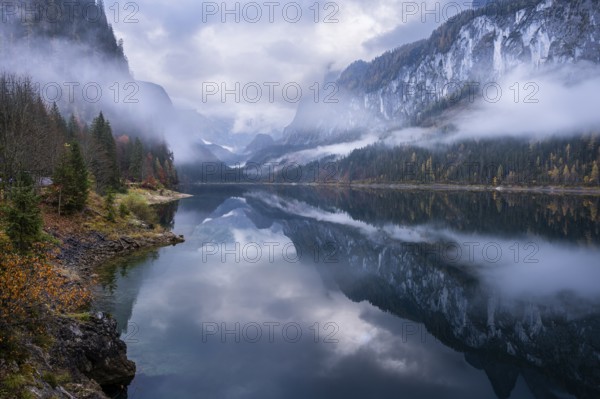 The Vordere Gosausee in autumn with a view of the Gosaukamm on the right. The Dachstein in clouds in the background. Cloudy sky. Overcast. Reflection. Vorderer Gosausee, Gosau, Gosau valley, Salzkammergut, Upper Austria, Austria, Europe