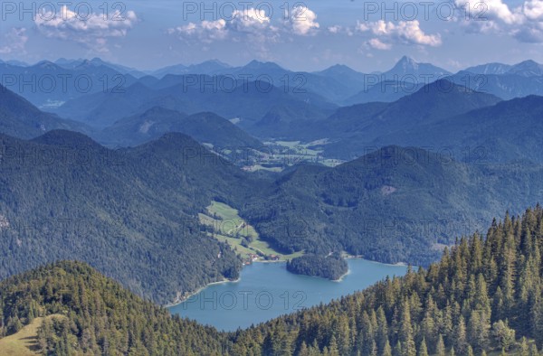 A wide panorama of mountains and valleys with extensive forests under a blue sky with clouds, Walchensee, Bavaria, Germany, Europe