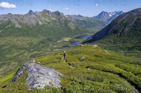 View of mountain landscape and valley with lakes, mountaineer on hiking trail to the summit of Rundfjellet, Svolvaer, Nordland, Norway, Europe