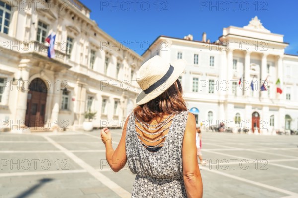 Woman tourist wearing straw hat walking in tartini square, piran, slovenia, enjoying summer holidays on adriatic coast
