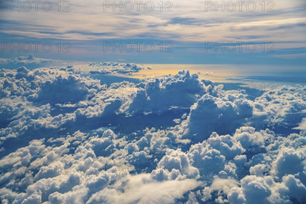Golden hour sunlight illuminates a vast expanse of fluffy white clouds over coron island, philippines, creating a breathtaking aerial view