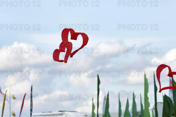 Two red heart-shaped kites flying intertwined in the sky, text free space, kite festival in Vinsebeck, Steinheim, Eggegebirge nature park Park and southern Teutoburg Forest, Weserbergland, North Rhine-Westphalia, Germany, Europe