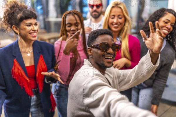 Multi-ethnic friends waving at camera taking selfie during a night party in a bar terrace