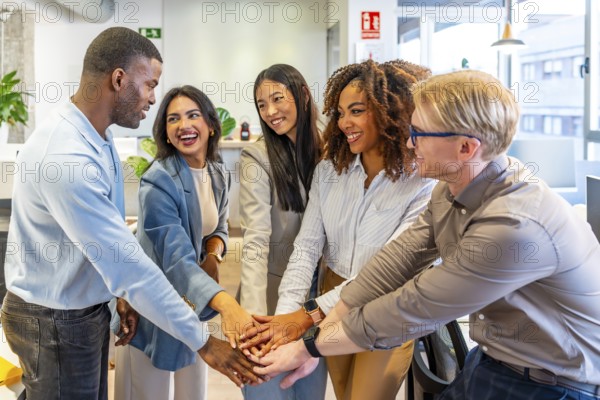 Coworkers joining hands in celebration, embodying success and teamwork within a vibrant, modern coworking office environment