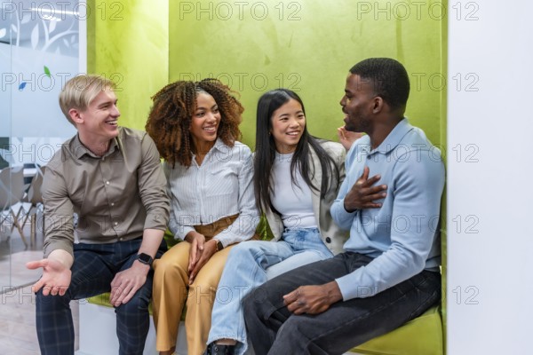 Four diverse colleagues enjoying a friendly conversation in a vibrant coworking space, fostering teamwork and collaboration