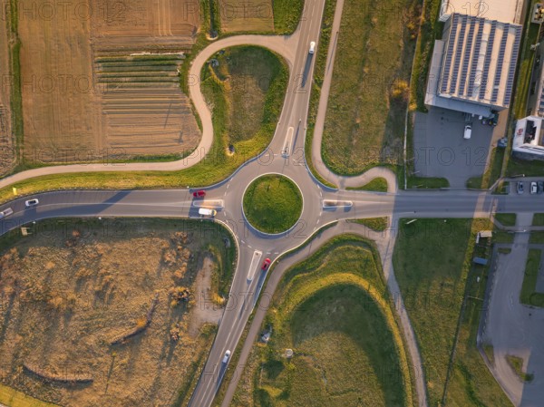 Aerial view of a roundabout surrounded by fields with several cars in the evening sun, Nagold, Black Forest, Germany, Europe