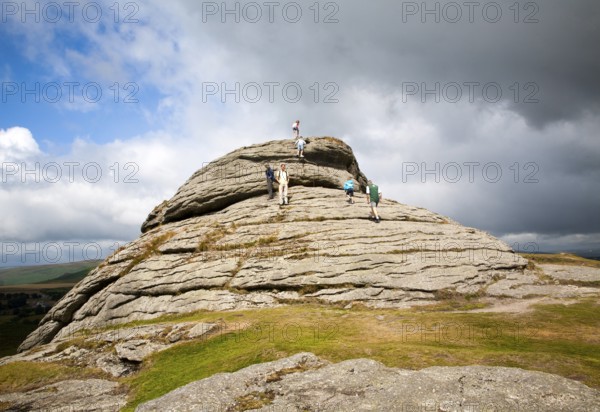 People scrambling on a granite tor near Haytor, Dartmoor national park, Devon, England, United Kingdom, Europe