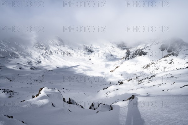 View of cloudy valley from the summit of Piz Laviner, mountain landscape in winter, Grisons Haute Route, Albula Alps, Rhaetian Alps, Grisons, Eastern Switzerland, Switzerland, Europe