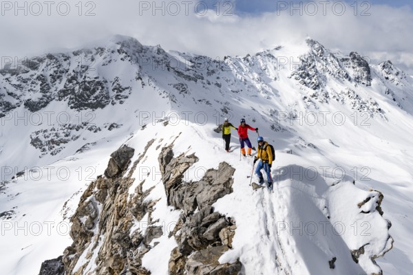 Three mountaineers climbing the narrow ridge of Piz Laviner, view of mountain panorama in winter mountain landscape, Grisons Haute Route, Albula Alps, Rhaetian Alps, Grisons, Eastern Switzerland, Switzerland, Europe
