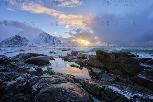 Beach of Norwegian sea on rocky coast in fjord on sunset in winter. Vareid beach, Lofoten islands, Norway, Europe
