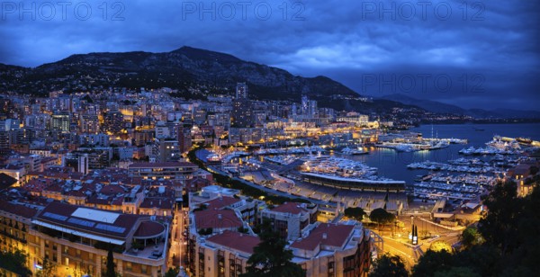 Aerial panorama of Monaco Monte Carlo harbour and illuminated city skyline in the evening blue hour twilight. Monaco Port night view with luxurious yachts