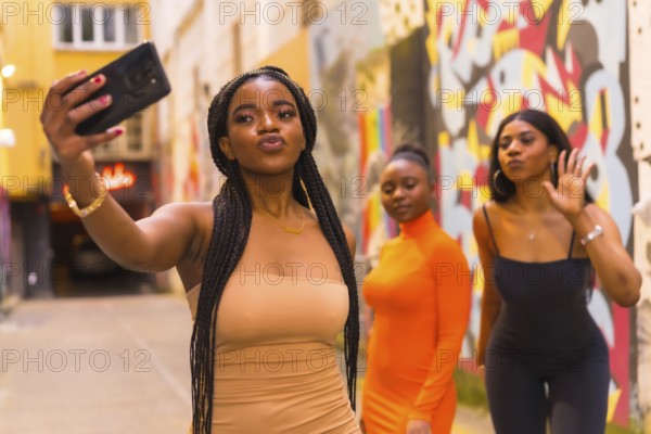 San Sebastián, Gipuzkoa Spain, February 2021: Three girls taking a selfie. Fashionable urban style with three black African girls on a city street, tight dresses