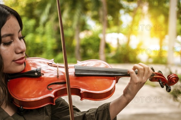 Close up of a girl with her violin playing a melody outdoors, Concept of smiling female violinist. Attractive girl playing the violin outdoors. Portrait of a girl playing the violin outdoors