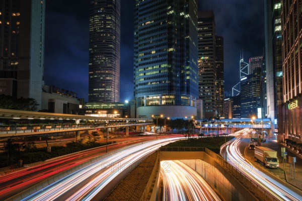 Street traffic in Hong Kong at night. Office skyscraper buildings and busy traffic on highway road with blurred cars light trails. Hong Kong, China, Asia