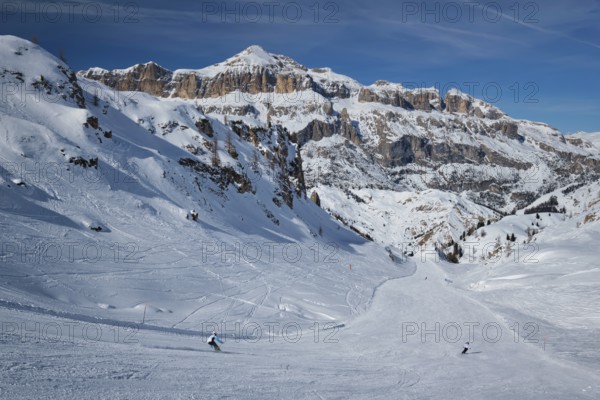 View of a ski resort piste with people skiing in Dolomites in Italy. Ski area Arabba. Arabba, Italy, Europe